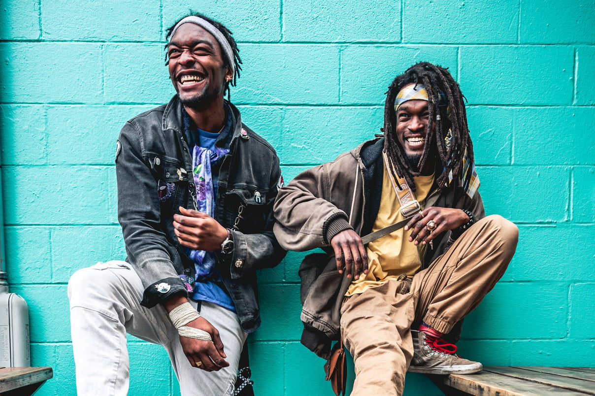 Cheerful black men leaning on bright wall